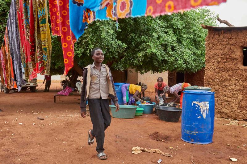 Boy walking under colorful fabric in an African village.