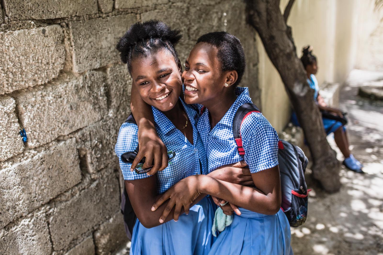 Two school girls hugging each other.