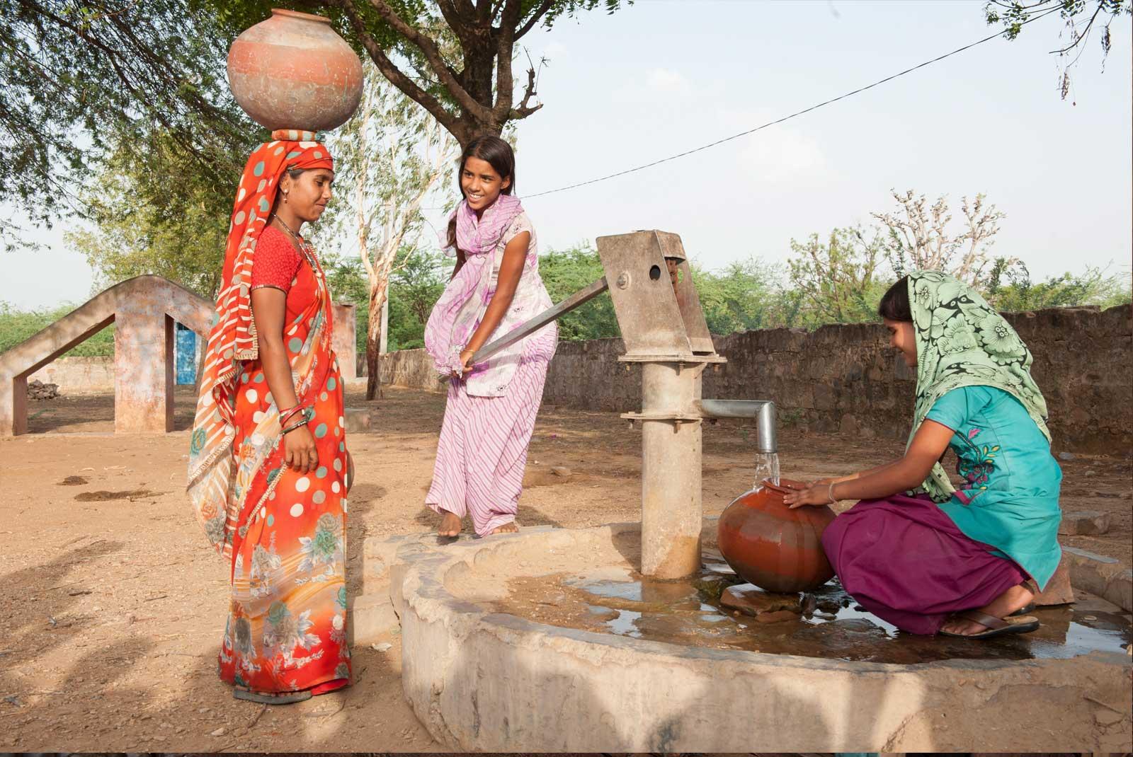 Three girls getting water from pump in India