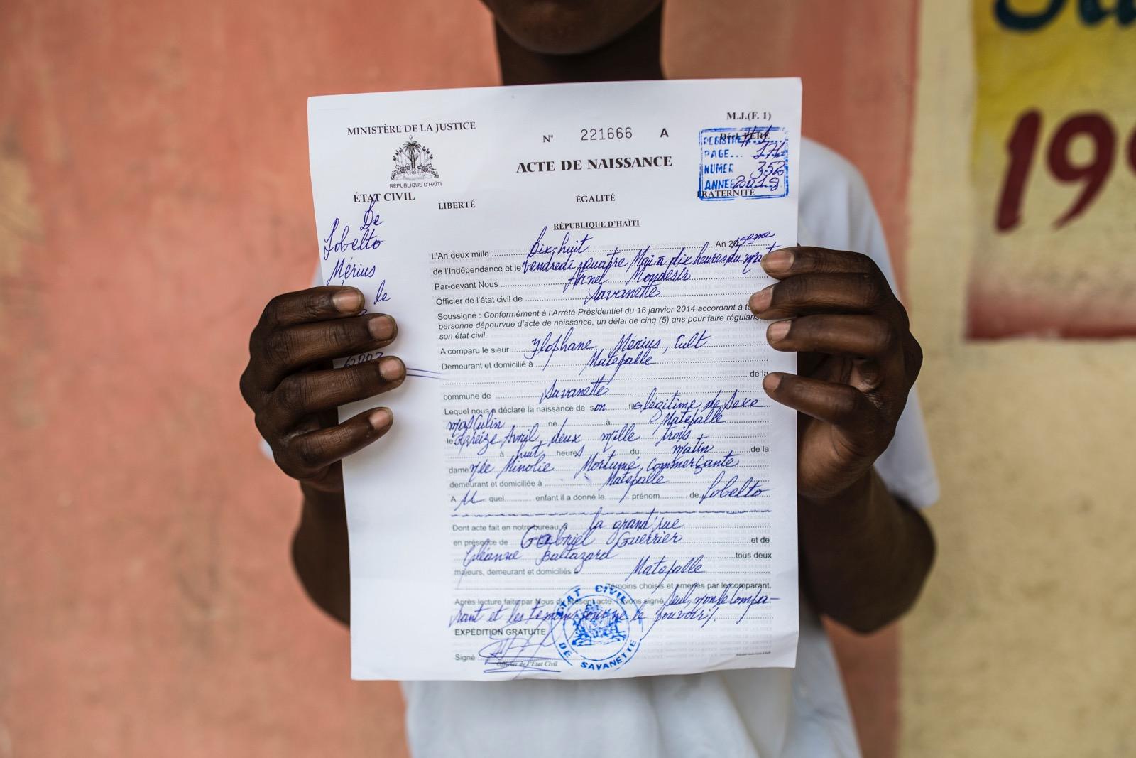 A boy holding up his birth certificate. 