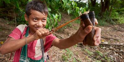 Boy with slingshot in rain forest
