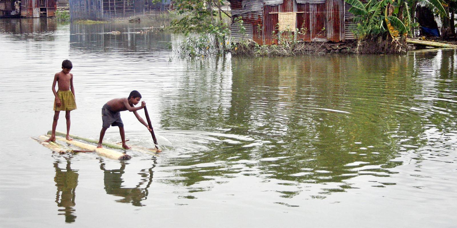 Boys on raft in flooded village.