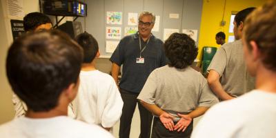 Javier Stauring speaks to children in juvenile hall unifroms, with hands on their backs. 