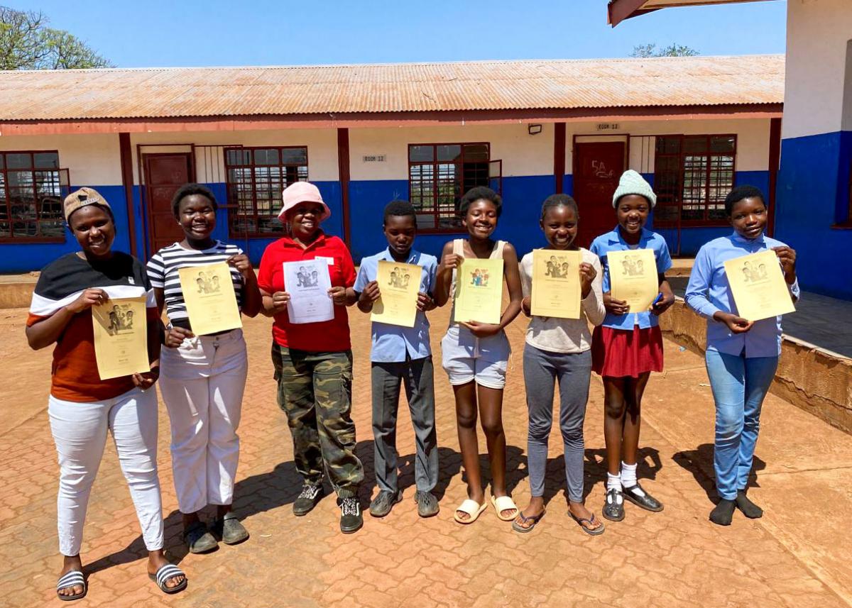 Children smiling, showing certificates in school yard.