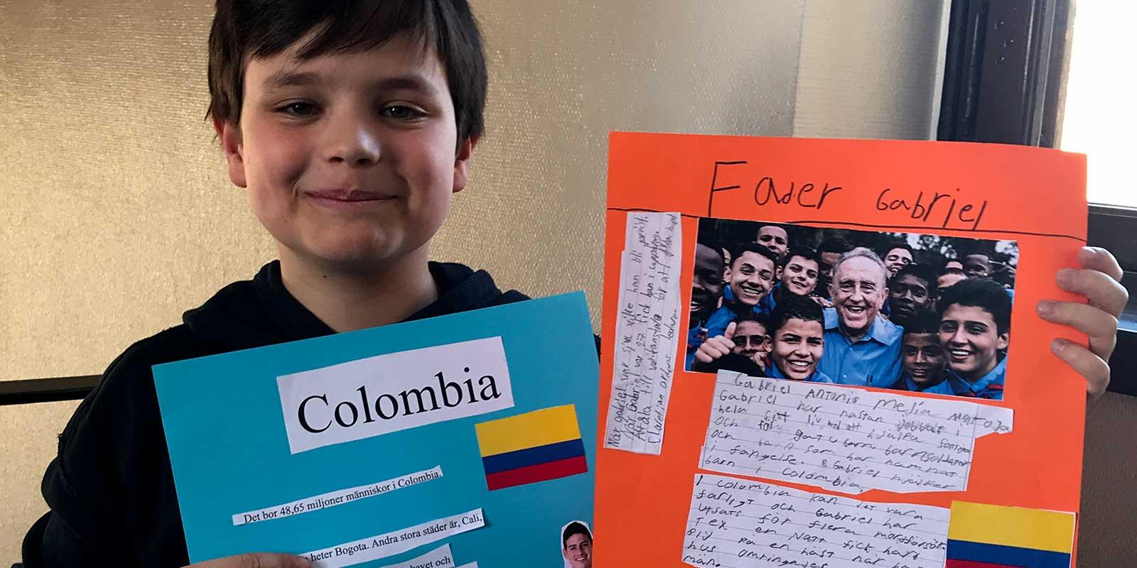Boy showing his school project, posters about Colombia.