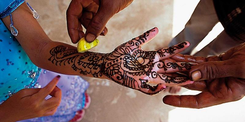 Girls hand being painted with henna