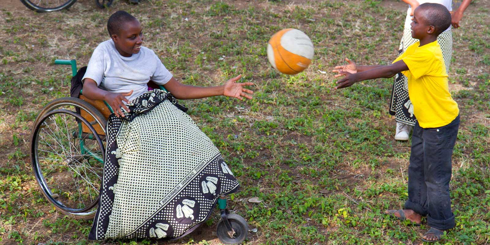 Girl in wheelchair playing ball with young boy