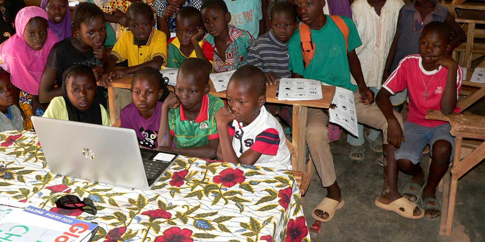 Children watching a computer screen in run -down classroom
