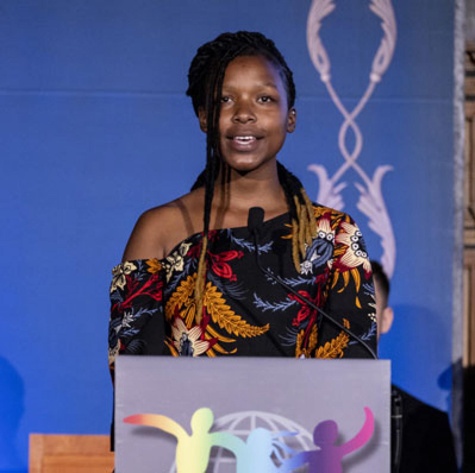 African girl speaks at podium. 
