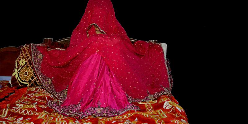 A girl sits covered on the floor, waiting to be married