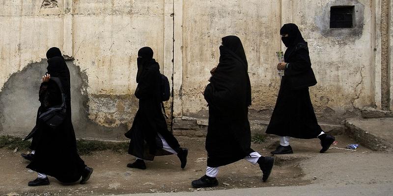 Schoolgirls in black walking along street