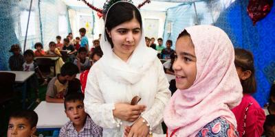 Malala holds the hand of a girl in a refugee camp