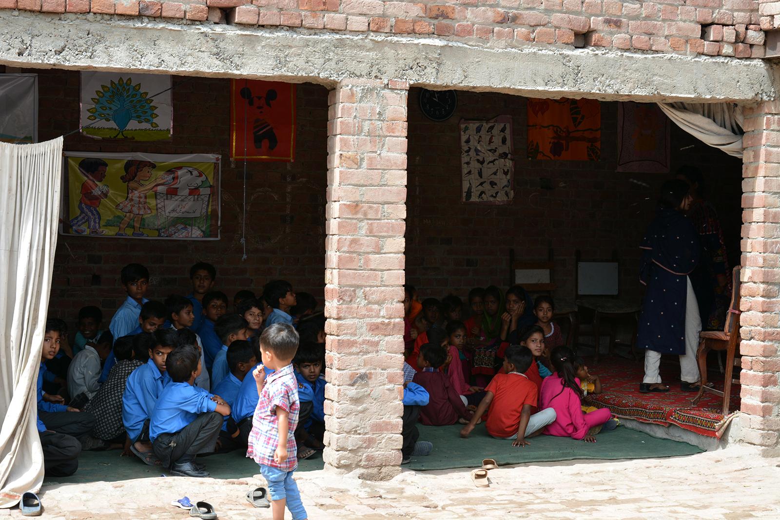 Children sitting inside a brick building