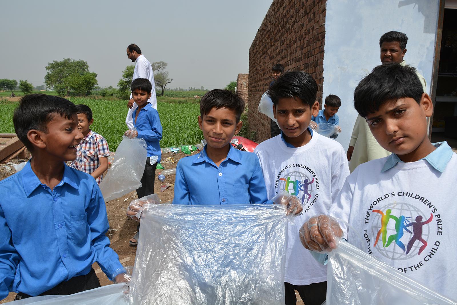 Boys looking into the camera, holding plastic bags