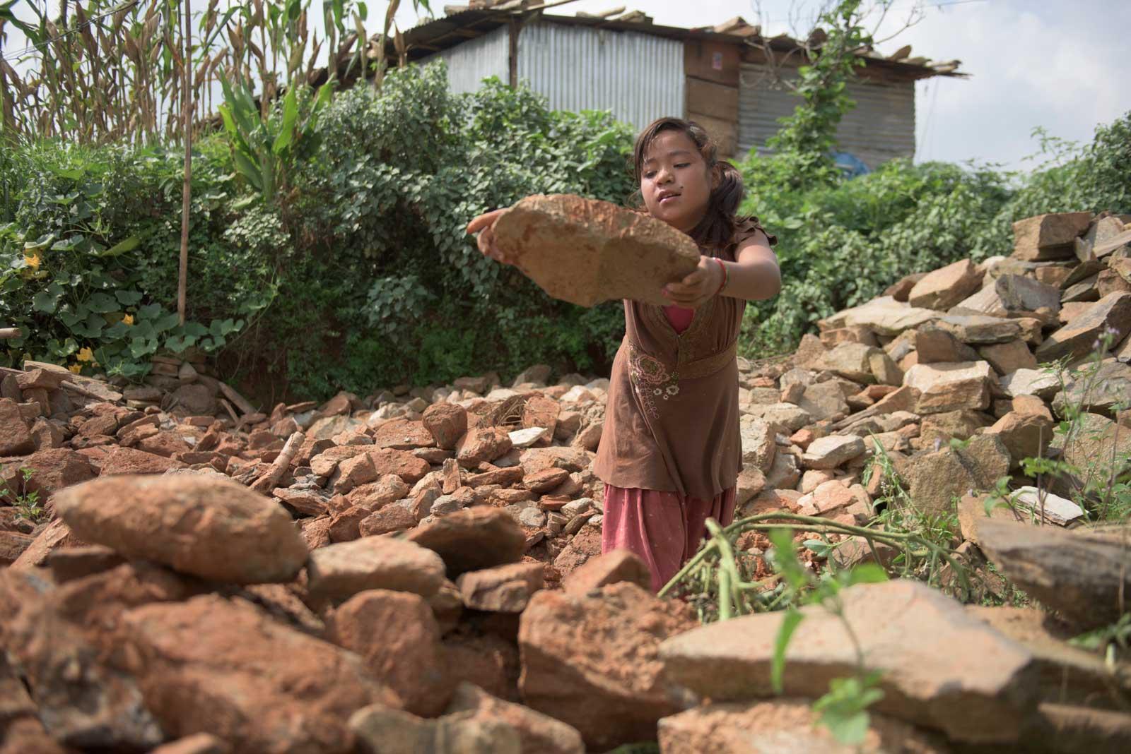 phulmaya cleaning up after earthquake, lifting stones