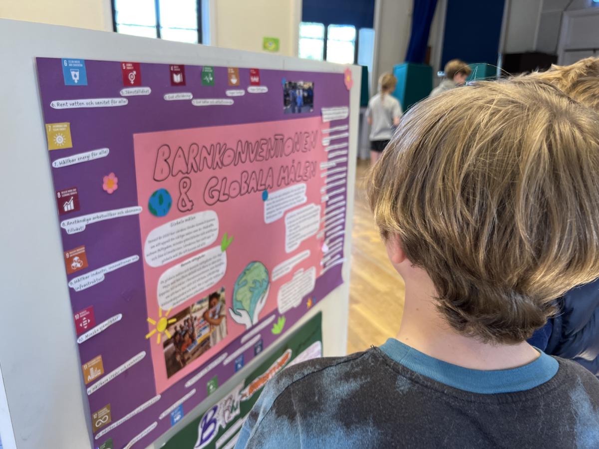 Pojke läser affisch om barnkonventionen och de globala målen.