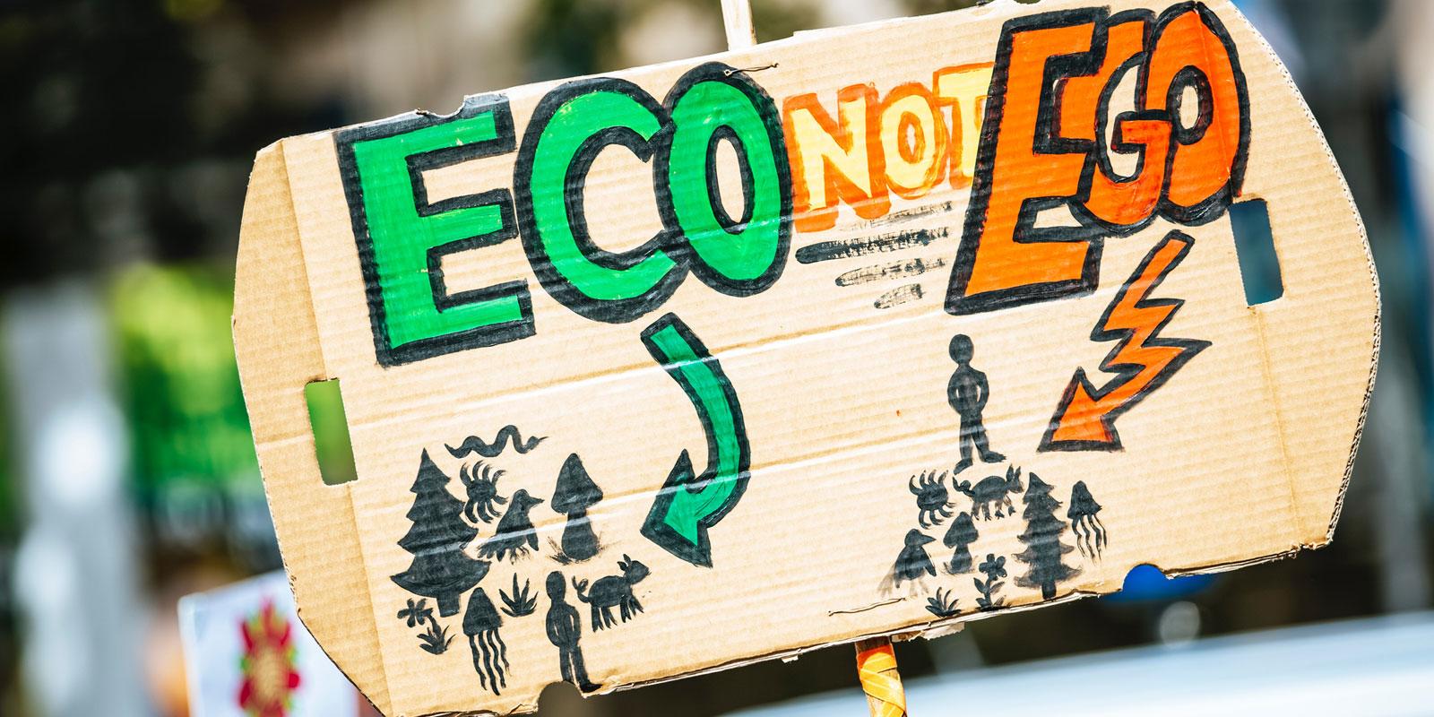 Person holding sign with text !ECO not EGO!.