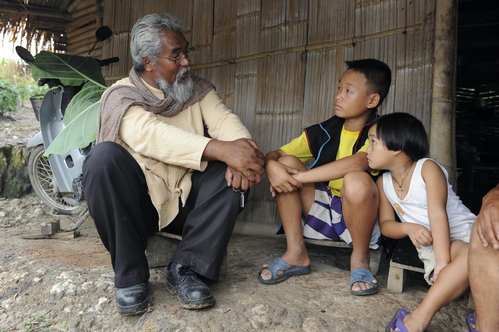 Sompop talking with children at their home