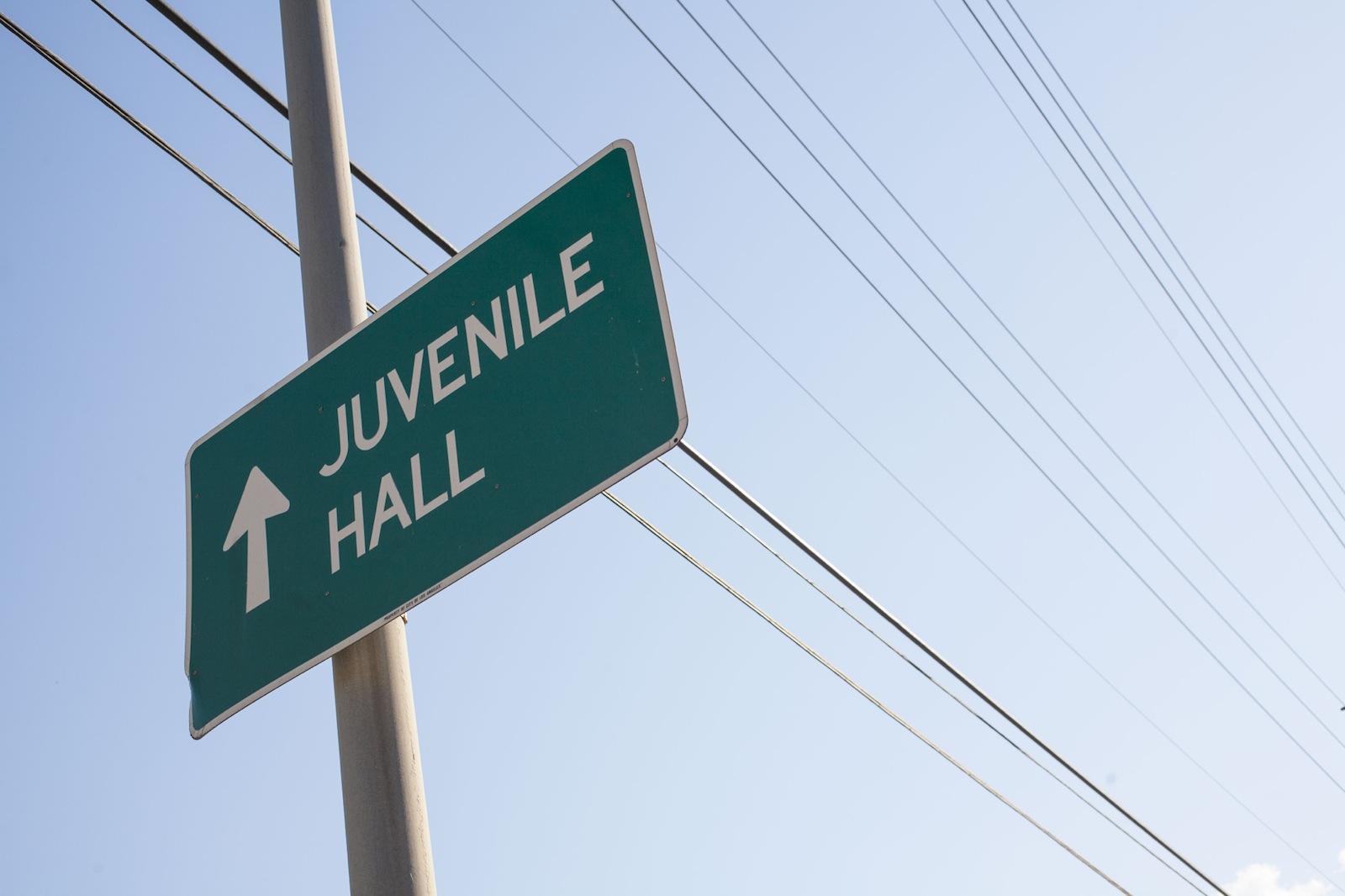 Green street sign with white text Juvenile Hall. 