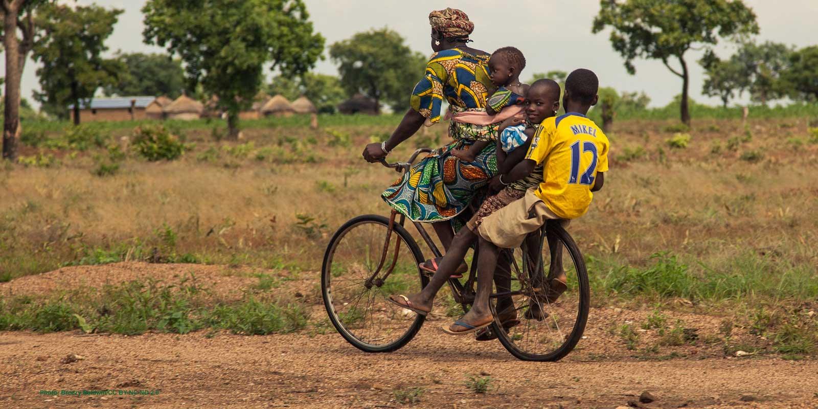 Woman riding bicycle with three kids in countryside