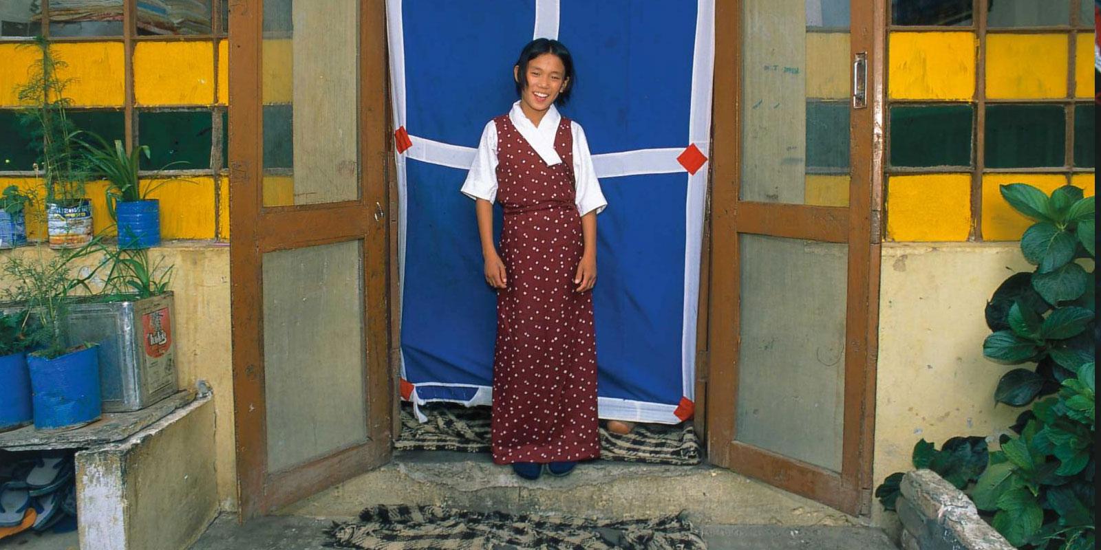 Girl standing in doorway with blue-wite-red drape.