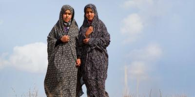 Two girls in shawls seen against blue sky. 