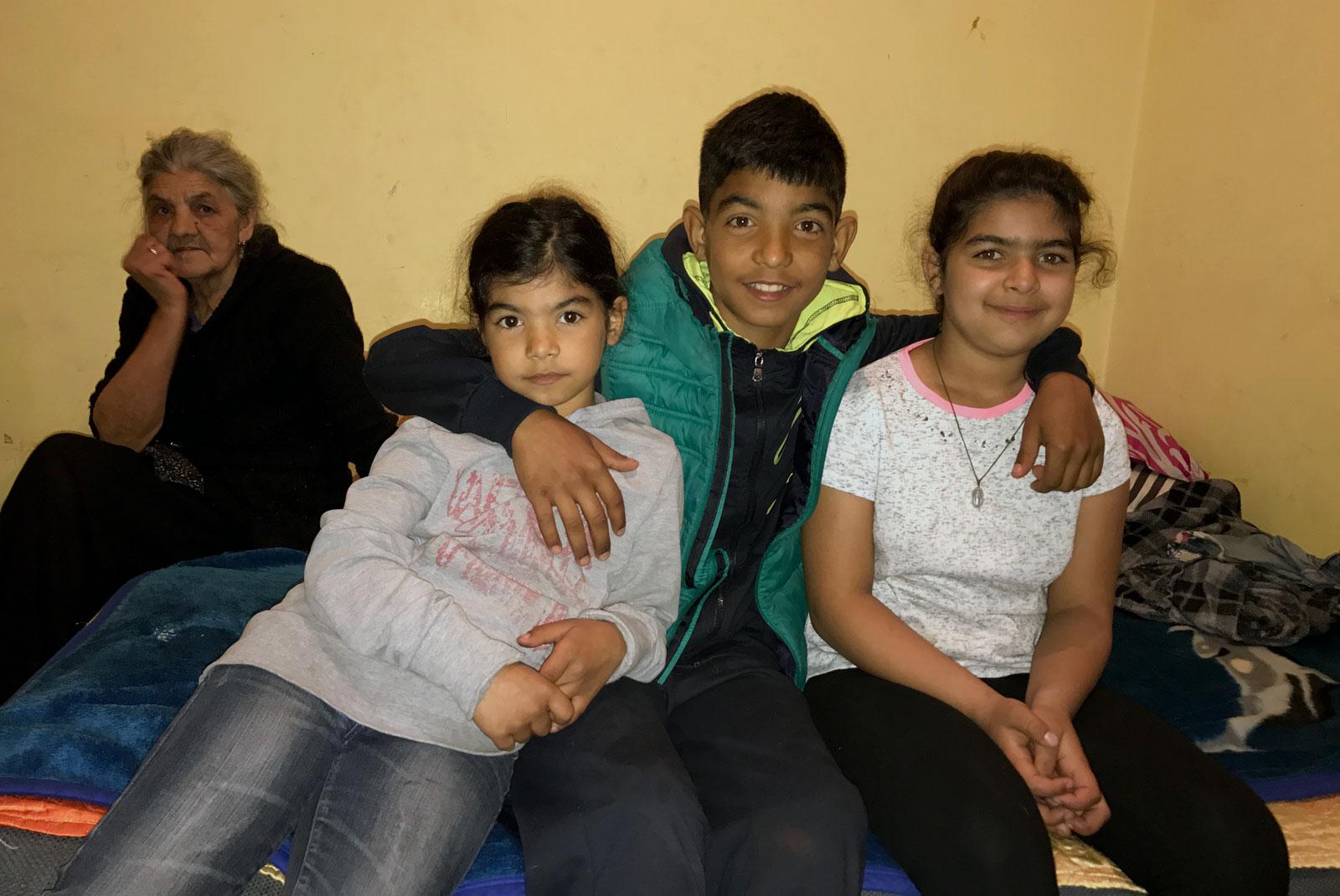 Bobbo, Zana and the family sit on the bed in their one-room apartment.